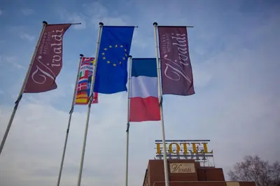three flags on poles in front of a hotel at Vivaldi Hotel in Westerlo