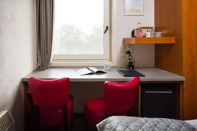 a room with a desk with red chairs and a window at Vivaldi Hotel in Westerlo