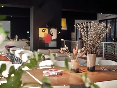 a table with white chairs and vases with flowers on it at BANKS Antwerp in Antwerp