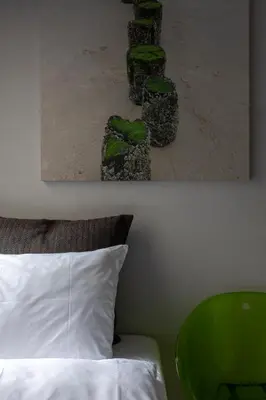 a bedroom with a bed with a green chair and a painting at BANKS Antwerp in Antwerp