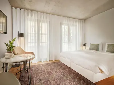 a white bedroom with a large bed and a table at BANKS Antwerp in Antwerp
