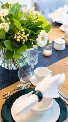 a table with plates and bowls and a vase with flowers at The Hamptons Boutique Hotel in Ghent