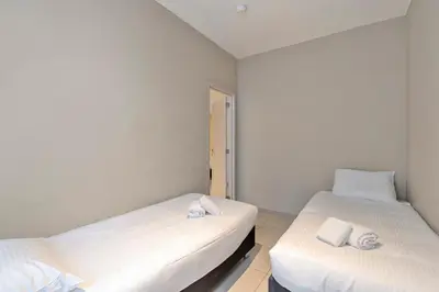 two beds in a room with white walls at Ambassador Suites Leuven in Leuven