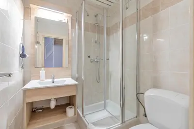 a bathroom with a shower and a toilet and a sink at Ambassador Suites Leuven in Leuven