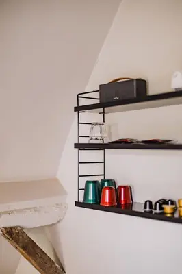 a shelf with four different colored cups on a wall at Burgstraat 8 in Ghent