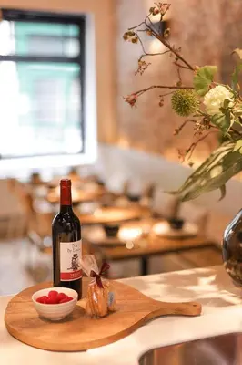 a bottle of wine and a bowl of fruit on a cutting board at Boutique Holiday Home Zalig In Antwerpen in Antwerp