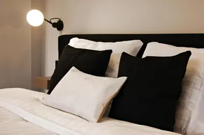 a bed with black and white pillows and a lamp at B&B VIENNA in Lokeren