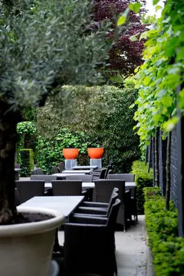 a row of tables and chairs with orange vases on them at B&B VIENNA in Lokeren
