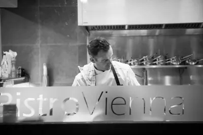 a man standing in a kitchen preparing food at B&B VIENNA in Lokeren