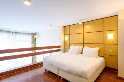 a bedroom with a white bed and a large window at B-aparthotel Montgomery in Brussels