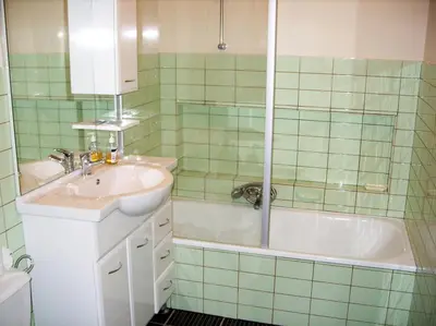 a green tiled bathroom with a sink and a tub at Budget Flats Antwerp in Antwerp