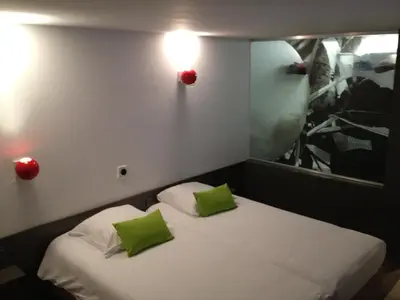 a room with a bed with two green pillows at Hotel Corbie Geel in Geel