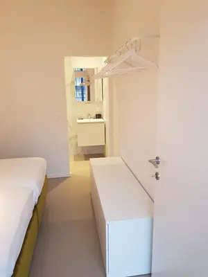 a white bedroom with a bed and a sink at Hotel Corbie Geel in Geel