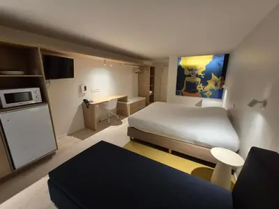 a small room with a bed and a kitchen at Hotel Corbie Geel in Geel