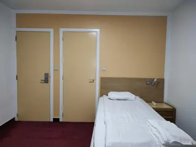 an empty room with a bed and two doors at Hotel Evergreen in Brussels