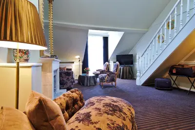 a living room with a couch and chairs and stairs at Hotel Manos Premier in Brussels