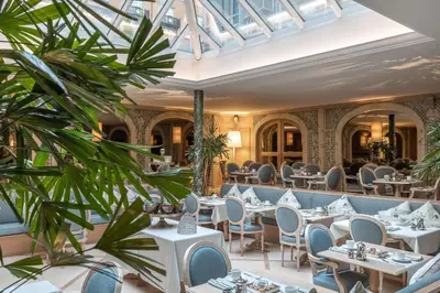 a restaurant with white tables and blue chairs at Hotel Manos Stephanie in Brussels