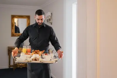 a man holding a tray with food on it at Hotel Manos Stephanie in Brussels