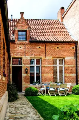 a brick house with chairs and a table in the yard at B&B De Vrome Vos in Mechelen