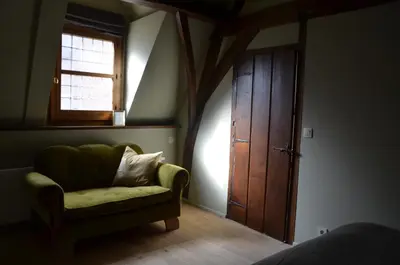 a bedroom with a green chair and a wooden door at B&B De Vrome Vos in Mechelen