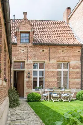 a brick house with a table and chairs in the yard at B&B De Vrome Vos in Mechelen