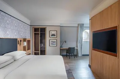 a bedroom with a large bed and a flat screen tv at Brussels Marriott Hotel Grand Place in Brussels
