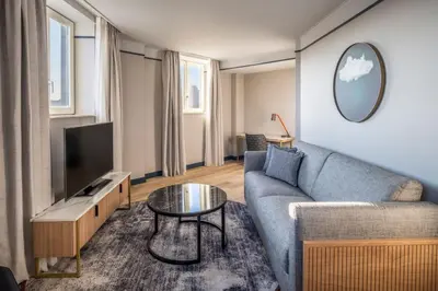 a living room with a couch and a tv at Brussels Marriott Hotel Grand Place in Brussels
