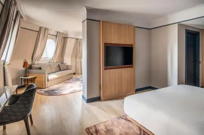 a bedroom with a bed and a tv and a couch at Brussels Marriott Hotel Grand Place in Brussels