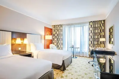 a hotel room with two beds and a desk at Renaissance Brussels Hotel in Brussels