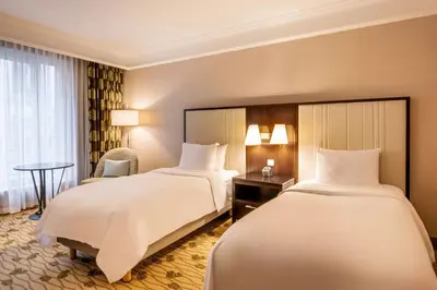 a hotel room with two beds and a chair at Renaissance Brussels Hotel in Brussels