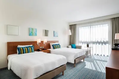 a hotel room with two beds and a desk at Courtyard By Marriott Brussels in Brussels