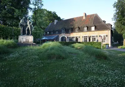 a statue in a field in front of a building at Hotel The Lodge Heverlee in Leuven