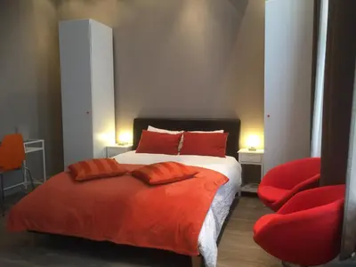 a bedroom with a bed and a red chair at Suite 11 in Antwerp