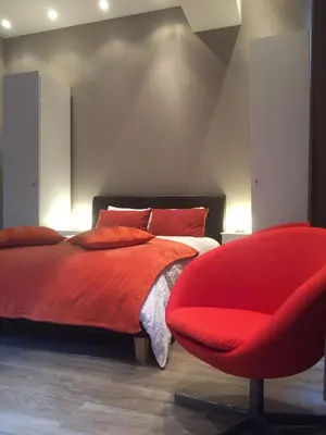 a bedroom with a red bed and a red chair at Suite 11 in Antwerp