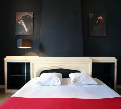 a bedroom with a white bed with a fireplace at Hotel La Royale in Leuven