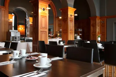 a dining room with tables and chairs in a restaurant at Hotel La Royale in Leuven