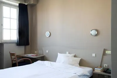 a hotel room with a bed and a table and a window at Hotel La Royale in Leuven