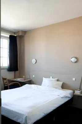 a hotel room with a white bed and a desk at Hotel La Royale in Leuven
