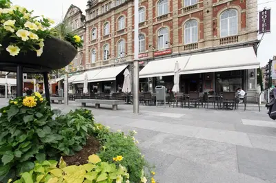 a street with tables and chairs in front of a building at Hotel La Royale in Leuven