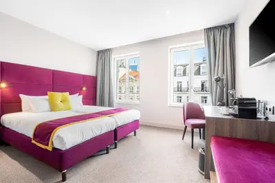 a hotel room with a purple bed and a desk at Marivaux Hotel in Brussels