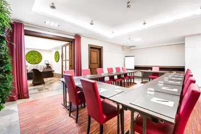a conference room with a long table and red chairs at Marivaux Hotel in Brussels