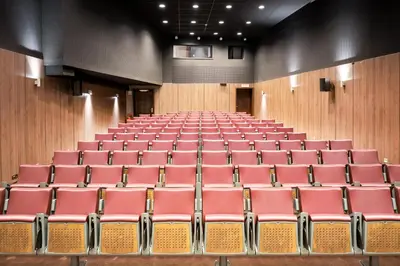 an empty auditorium with red chairs in the middle at Marivaux Hotel in Brussels