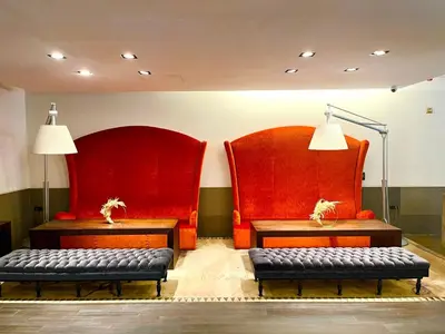 two red chairs and two benches in a room at Marivaux Hotel in Brussels