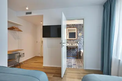 a living room with a blue couch and a bathroom at Hygge Hotel in Brussels