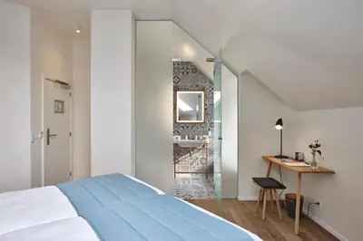 a bedroom with a bed and a desk and a mirror at Hygge Hotel in Brussels