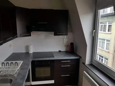 a small kitchen with black cabinets and a window at Central Yellow Apartment in Brussels
