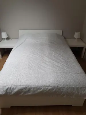 a white bed in a room with two tables at Central Yellow Apartment in Brussels