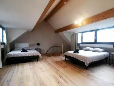 two beds in a room with wooden floors and windows at Parlamentarium apartment in Brussels