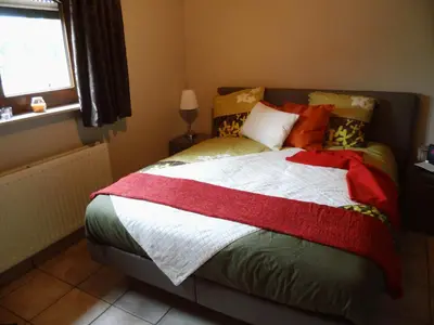 a bedroom with a bed with colorful pillows and a window at Relax Garden in Hulshout