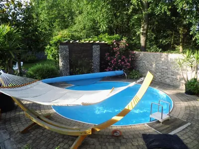 a hammock sitting next to a swimming pool at Relax Garden in Hulshout